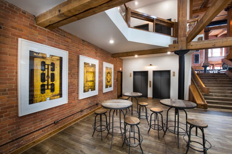 Lower lobby to The Globe Building set with three high top tables and barstools and art on the walls.