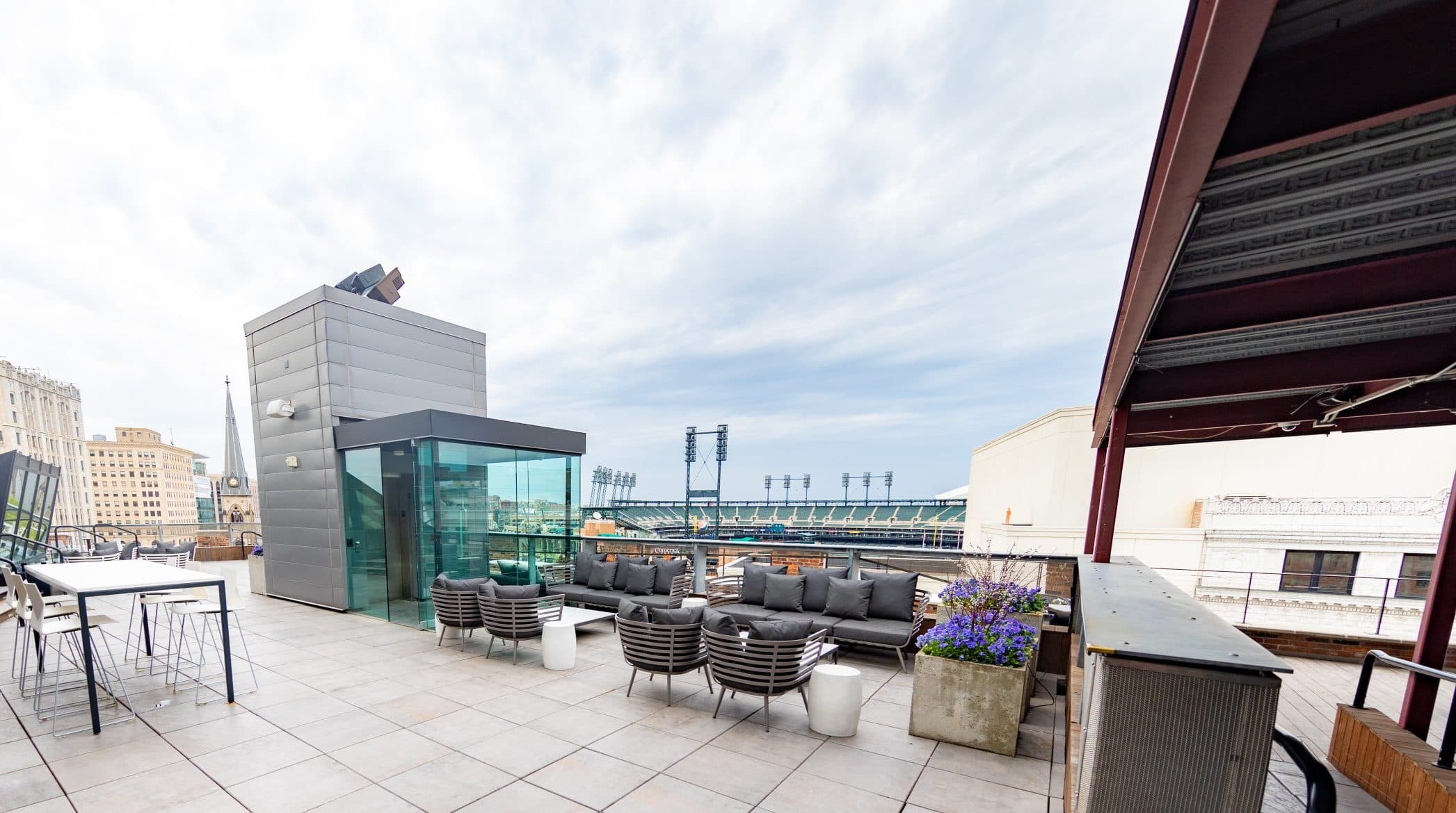 Furniture grouping, communal table and live planters set near elevator bank on The Madison Rooftop in Detroit."