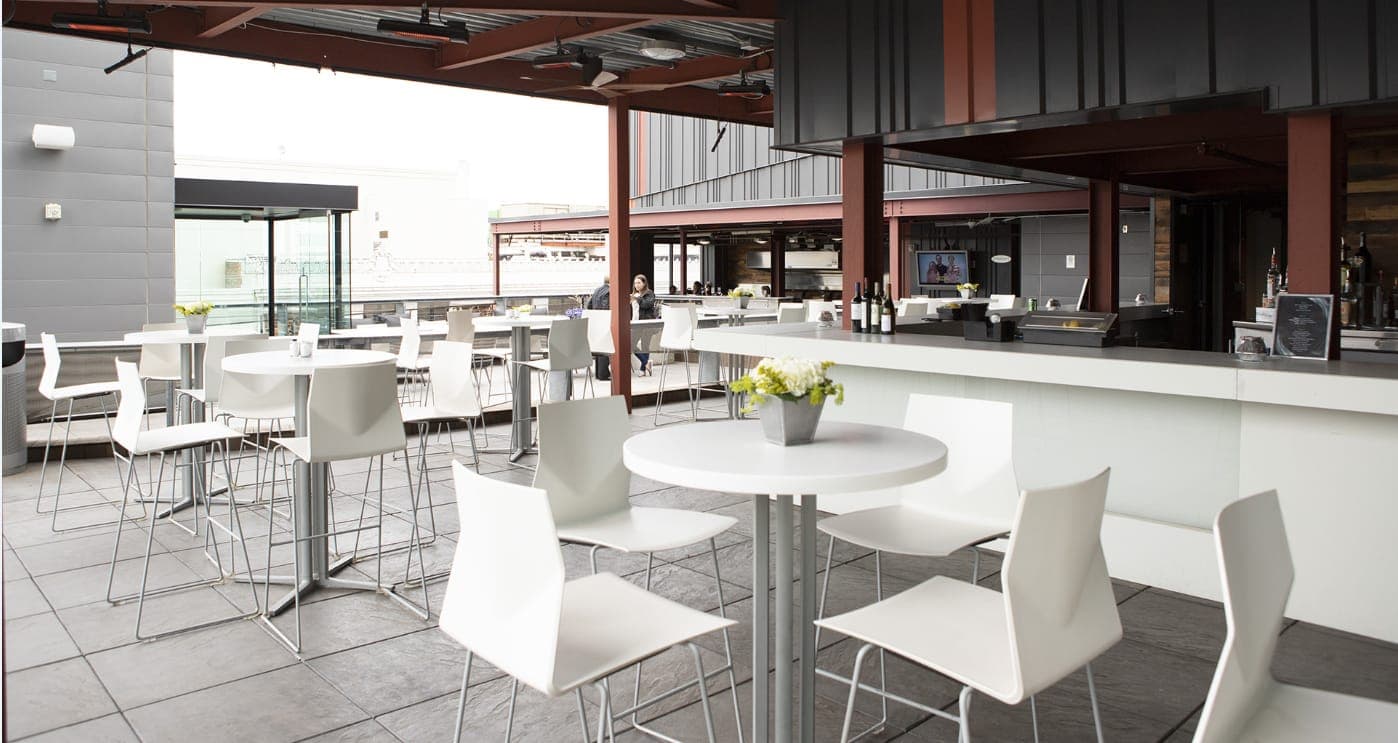 High-top tables and barstools set near built-in bar at The Madison Rooftop in downtown Detroit.
